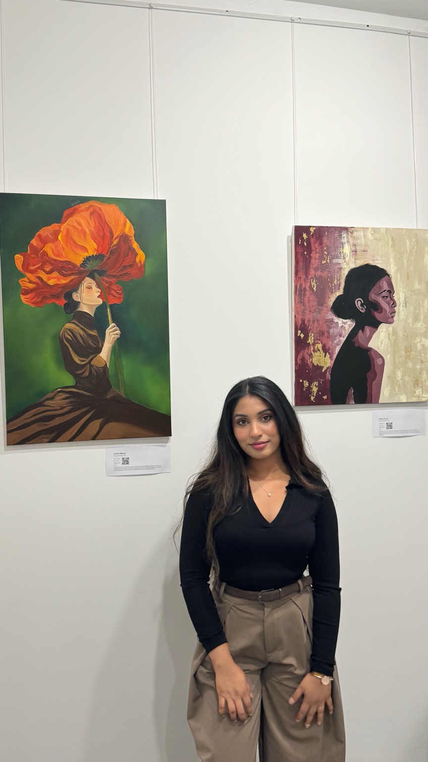 Shehara in front of two paintings at the Materiality exhibition